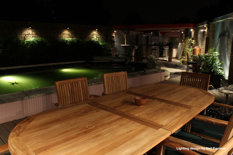 teak garden table and chairs set in a beautifully lit garden