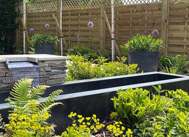 low garden walls covered with dark coloured porcelain cladding make an elegant water feature