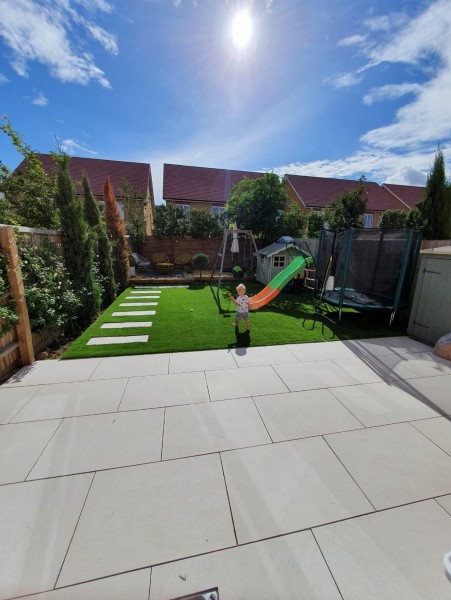 large buff coloured porcelain patio overlooking neat lawned garden