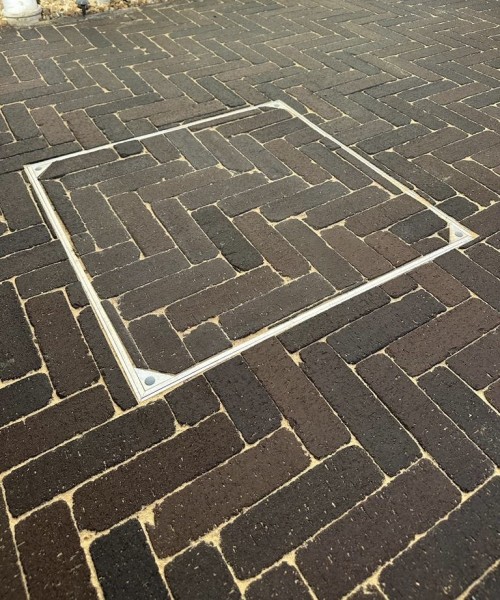double sealed recessed manhole cover inserted into brick paved area
