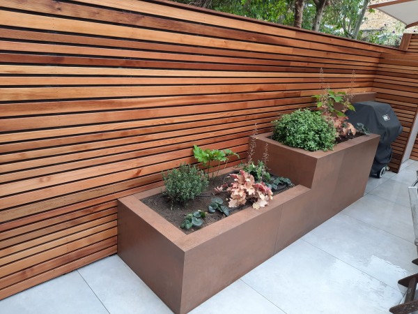 staggered height rectangular planters in front of cedar fence