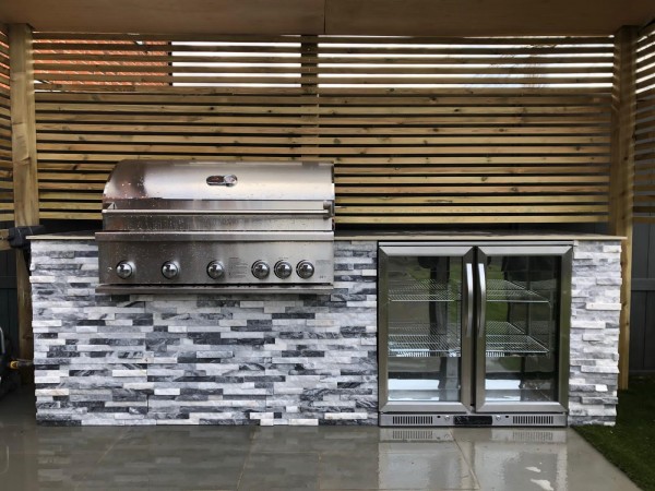 stainless steel outdoor kitchen units surrounded by silver grey split face stone tile cladding