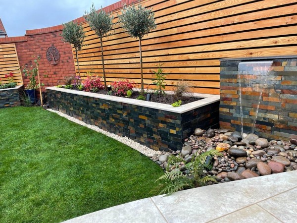 raised bed clad with split face stone in dark grey colour