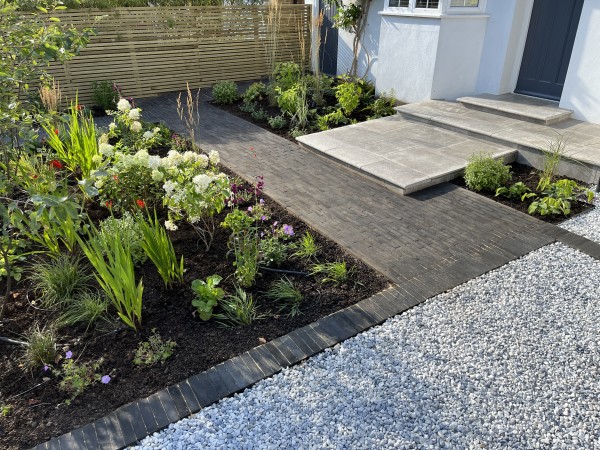 attractive dark grey limestone path with planted beds either side