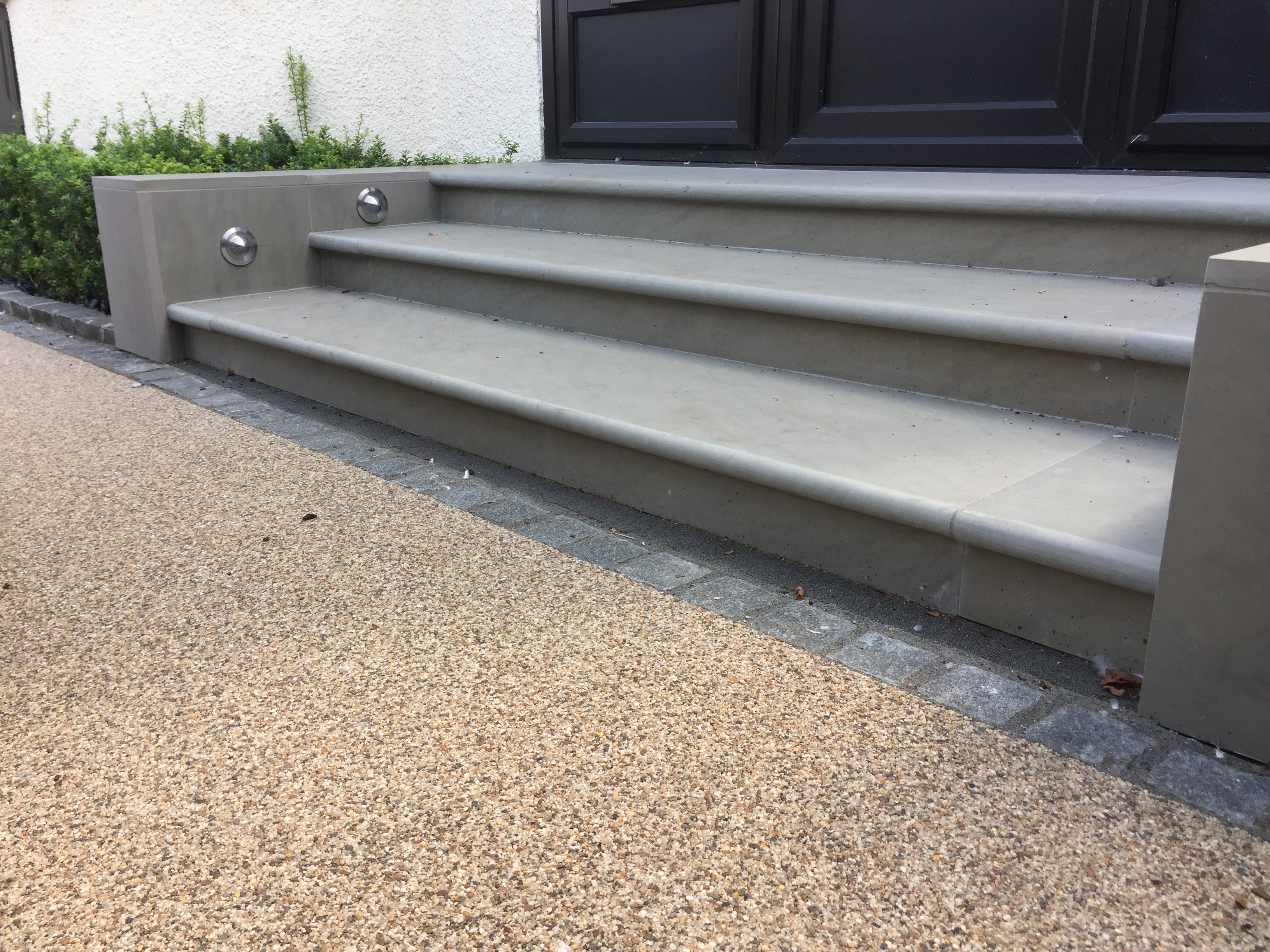 buff coloured resin bound driveway with limestone steps up to a terrace