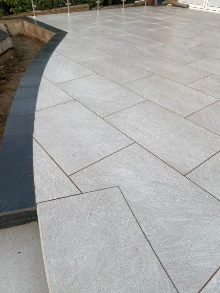 curved patio created from sabbiosa grigio porcelain pavers in light grey colour