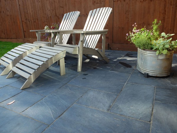 Sawn midnight black slate paving patio with stylish loungers