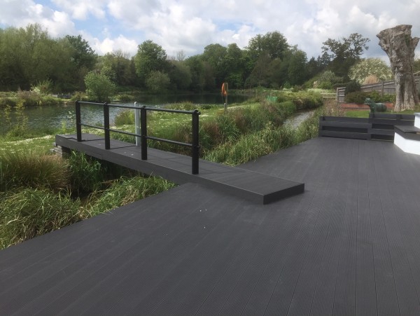 Large charcoal coloured decking area overlooking beautifully landscaped gardens