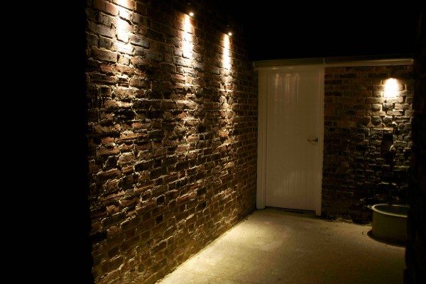 Outdoor path beside stone wall lit using wall mounted down lights