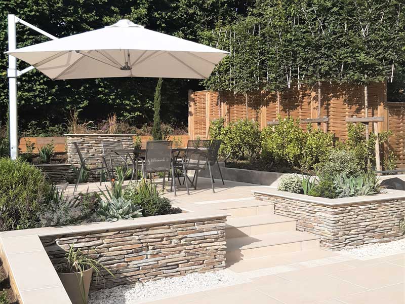 lovely mediterranean style patio surrounded by paddlestone walling designed by Anna Helps