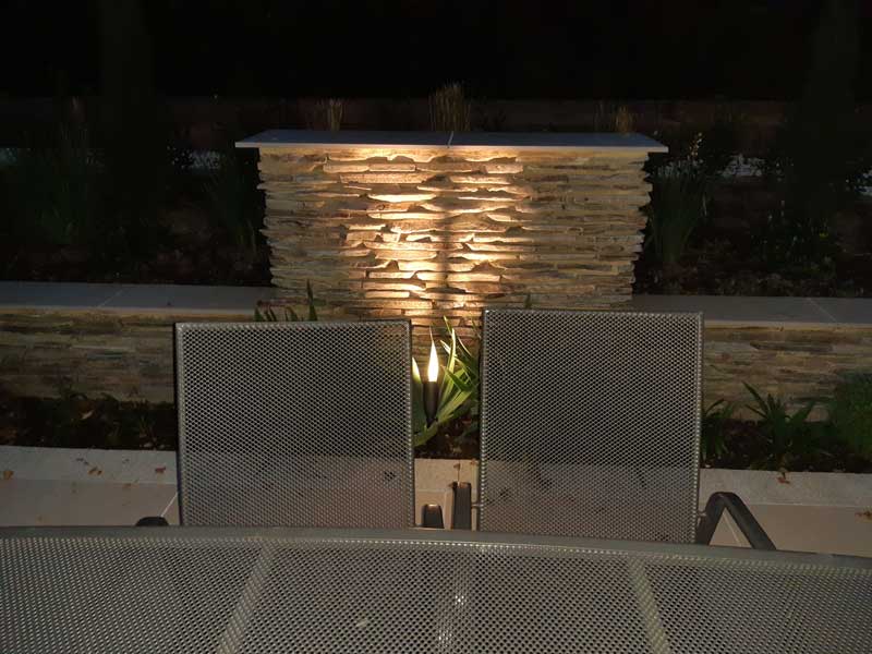 Paddlestone garden feature lit for evening use. Flame effect light enhances the texture of the stone.