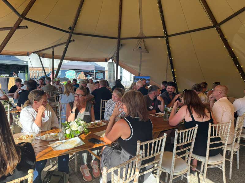 group of garden designers and landscapers networking over a sit-down meal in a teepee