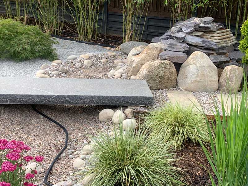japanese style gravel garden with dry river bed crossed by a bespoke granite bridge