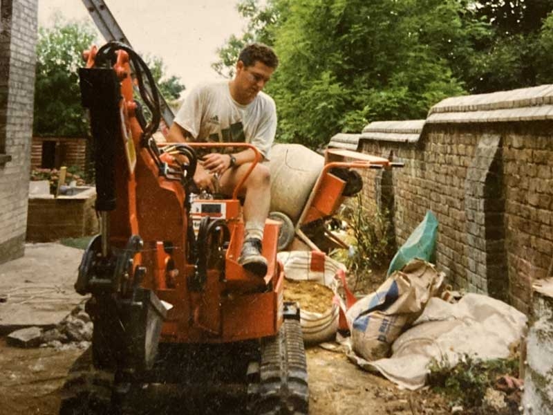 A young Richard Bickler driving a mini digger on a landscaping site