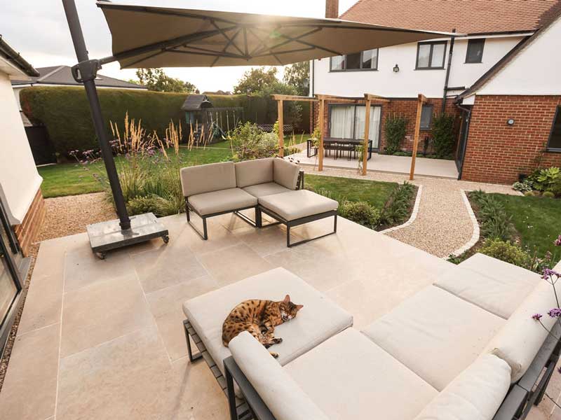 honed limestone patio designed by Heartwood Garden Design and enjoyed by the homeowners ginger cat