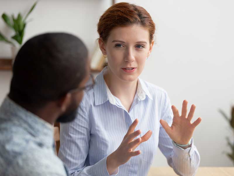 female garden designer in a striped shirt talking to their client about budgets
