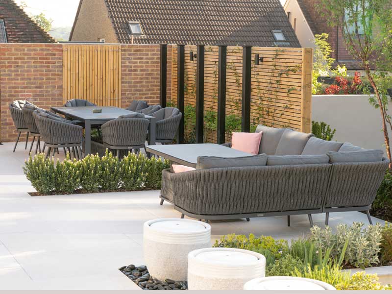 attractive garden terrace with light coloured paving and low privet hedge to divide the area into zones