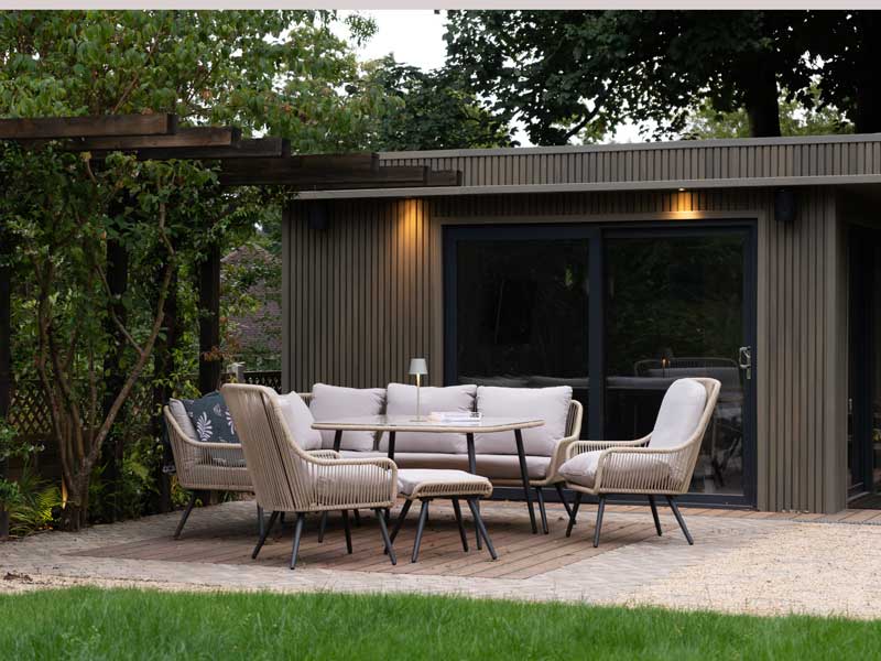 cosy contemporary garden room with timber cladding and furnished cream coloured patio to the front