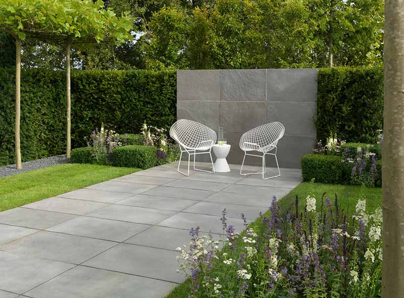natural limestone paving in a modern garden with formal yew hedges and pleached trees