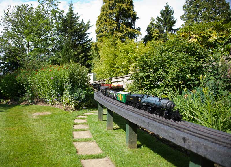 outdoor miniature railway track running through a garden