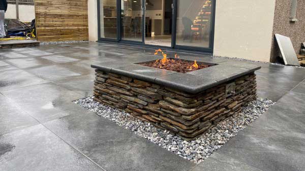 stylish patio with paddlestone firepit. Pavers are dark grey fusion graphite porcelain paving from Arbour Landscape Solutions