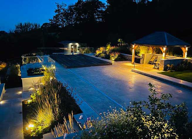 beautifully landscaped pool area with pergola, porcelain paving, plants and lighting