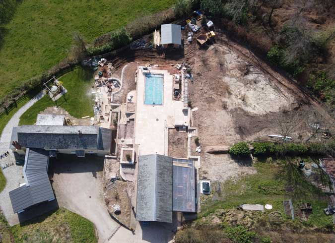 large landscaping site viewed from above showing property, swimming pool and bare land