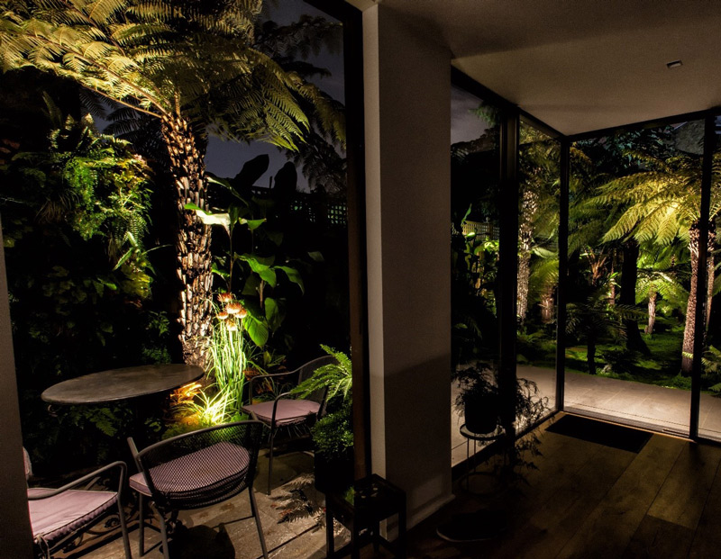 looking out onto a beautifully lit garden at night time