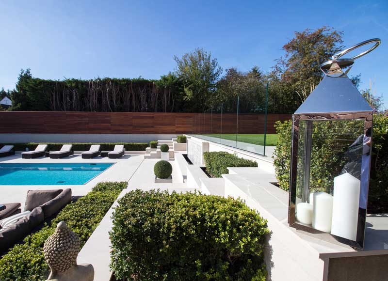 poolside garden with white stonework and green foliage for a simple colour palette