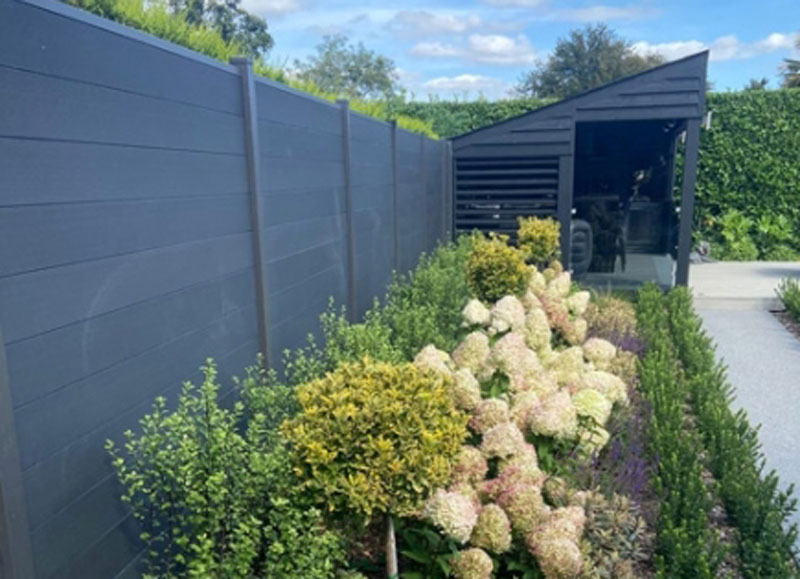 dark coloured composite fencing as a backdrop for vibrant planting