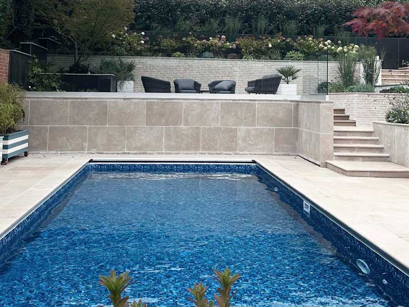 garden swimming pool with bespoke limestone surround and elegant steps to an upper garden terrace
