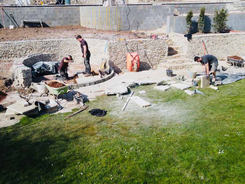 landscapers working on a complex project with retaining walls, terraces and circular features