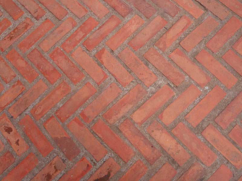 red landscaping bricks laid in a herringbone fashion with wider than standard joints