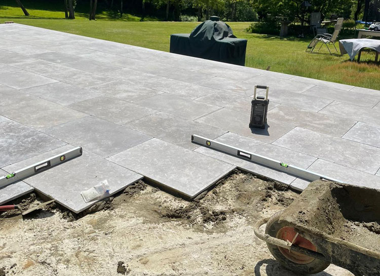 partially completed patio with landscaping tools in the foreground