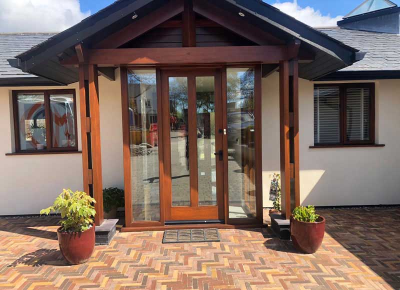 front door of self build property with timber framed porch and clay pavers creating wide walkway