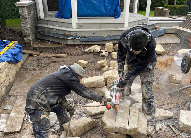 two landscapers using angle grinders to cut purbeck stone 