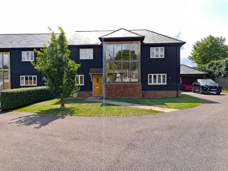 Newbuild property with black timber cladding and utilitarian front garden