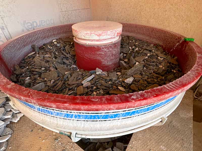 large circular machine filled with flat stones, the machine tumbles the stones to create a textured edge popular with landscapers and garden designers