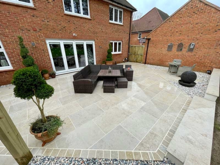 large porcelain patio with two seating areas and stylish topiary in pots