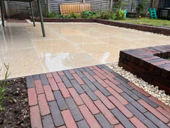 path made with red clay pavers leading to buff coloured limestone patio