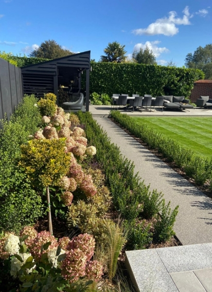 modern family garden with black composite fence to the left hand side, contemporary shelter and large lawn 