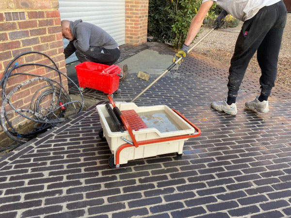 The raimondi pedalo washboy grouting tools being used to clean a newly laid brick paver driveway