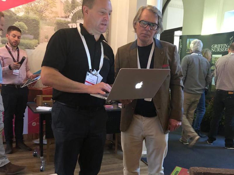 Richard Bickler in discussion with a garden designer both looking at laptop screen