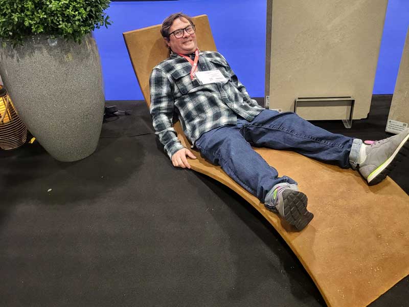 male garden designer in a plaid shirt laying on a lounger beside a potted plant