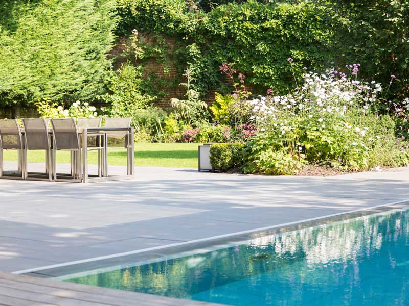 swimming pool in a typical english country garden with adjacent outdoor dining area and manicured lawns