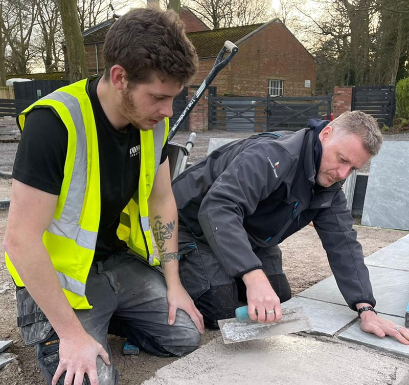 Gareth Wilson training a young landscaper in the art of laying pavers